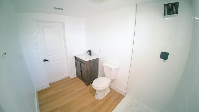 bathroom featuring toilet, baseboards, wood finished floors, and vanity