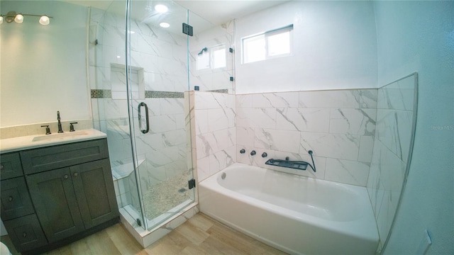 bathroom with a marble finish shower, vanity, a bath, and wood finished floors