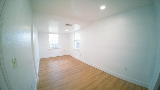 empty room with recessed lighting, wood finished floors, visible vents, and baseboards