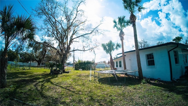 view of yard featuring a trampoline and fence