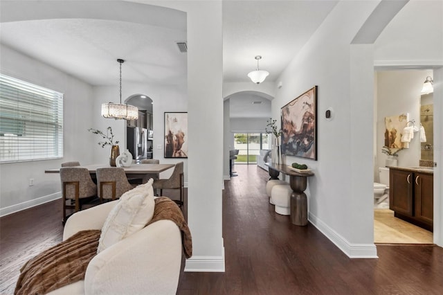 corridor featuring baseboards, arched walkways, and wood finished floors