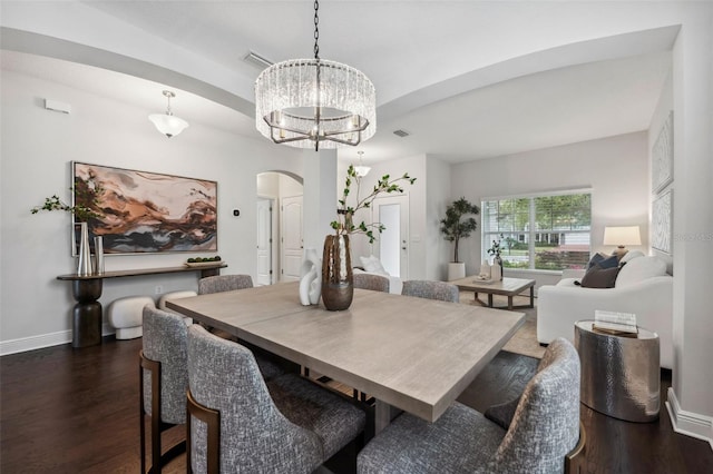 dining room with arched walkways, a notable chandelier, dark wood finished floors, visible vents, and baseboards