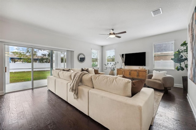 living area with dark wood-style floors, a ceiling fan, visible vents, and baseboards