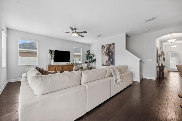 living area with baseboards, visible vents, a ceiling fan, arched walkways, and dark wood-type flooring