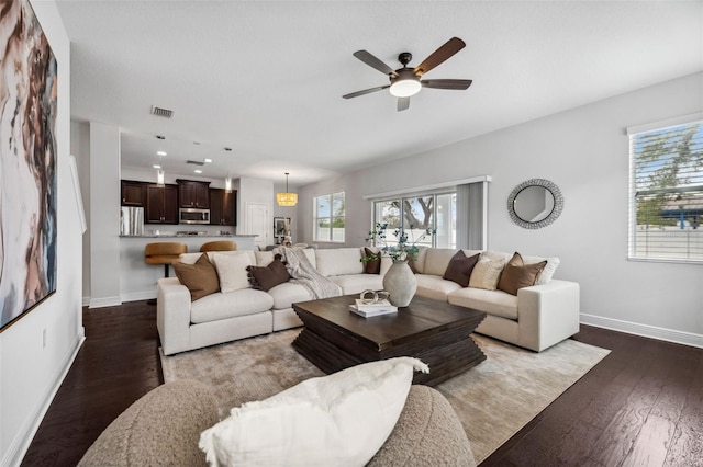 living area featuring plenty of natural light, baseboards, and dark wood-style flooring