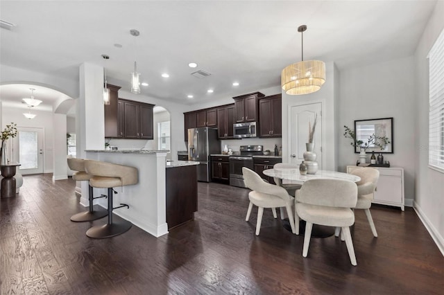 kitchen with arched walkways, stainless steel appliances, visible vents, dark brown cabinets, and a peninsula