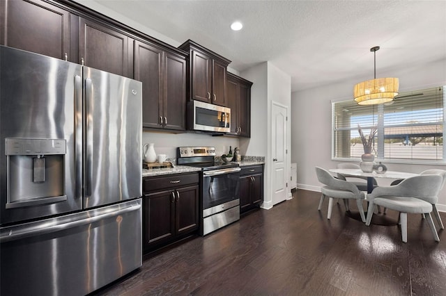 kitchen featuring stainless steel appliances, baseboards, dark brown cabinets, light stone countertops, and dark wood finished floors