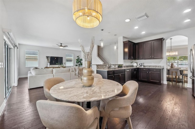 dining room featuring arched walkways, dark wood-style flooring, and recessed lighting