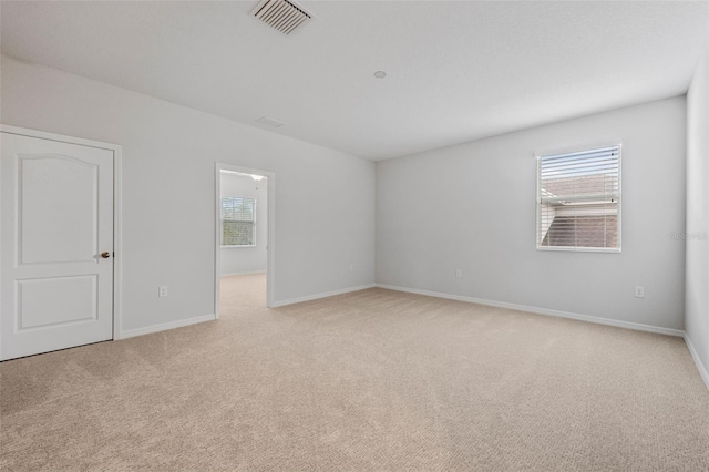 empty room with visible vents, light carpet, and baseboards