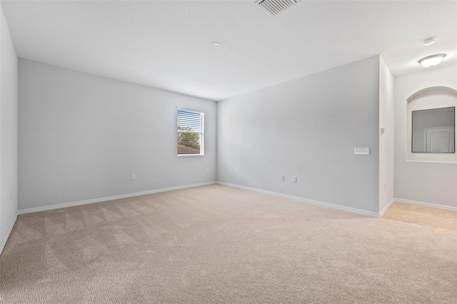 unfurnished room with baseboards, visible vents, and light colored carpet