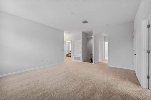 unfurnished living room featuring arched walkways, light carpet, visible vents, and baseboards