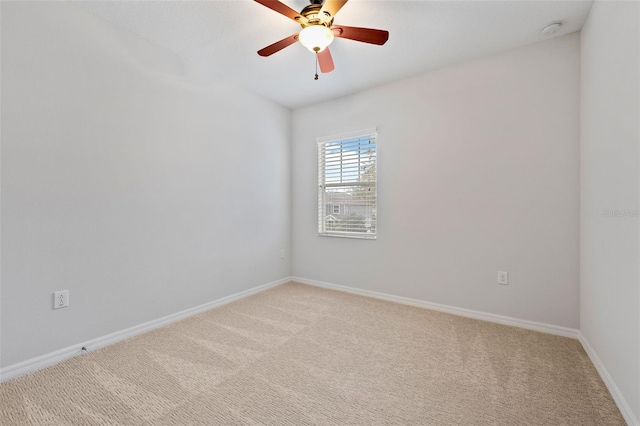 spare room featuring light carpet, ceiling fan, and baseboards