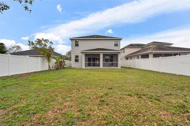 rear view of house with a lawn, a fenced backyard, and a sunroom