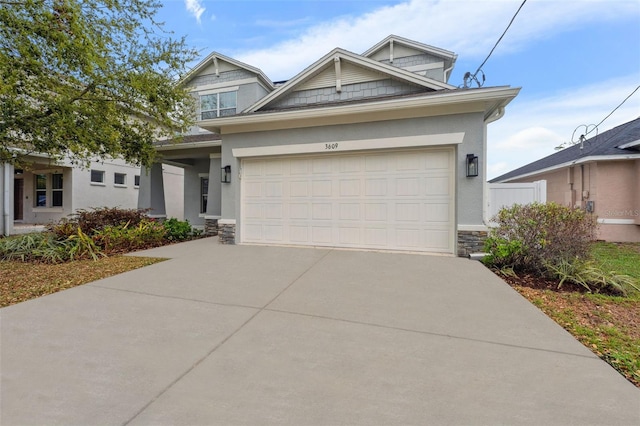 craftsman inspired home with a garage, stone siding, concrete driveway, and stucco siding