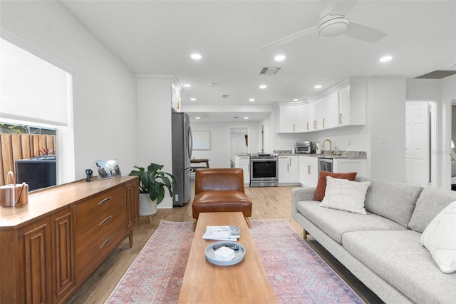 living room with visible vents, a ceiling fan, light wood-type flooring, indoor wet bar, and recessed lighting