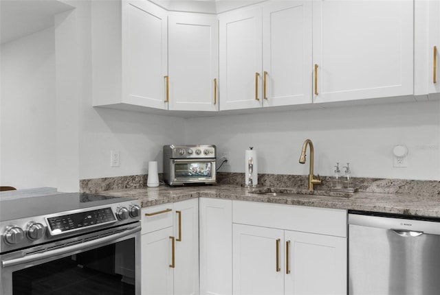 kitchen featuring appliances with stainless steel finishes, white cabinets, and a sink