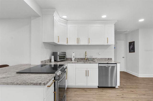 kitchen with stainless steel appliances, white cabinets, a sink, and light stone countertops