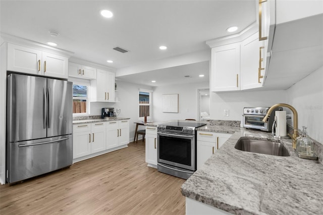 kitchen featuring white cabinetry, appliances with stainless steel finishes, light stone counters, and a sink