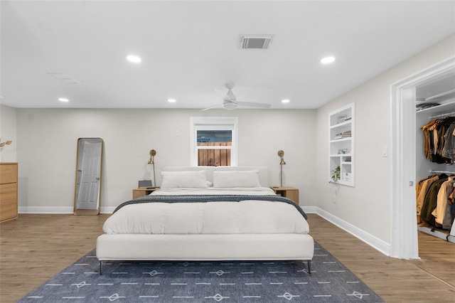 bedroom featuring arched walkways, dark wood finished floors, visible vents, and a walk in closet