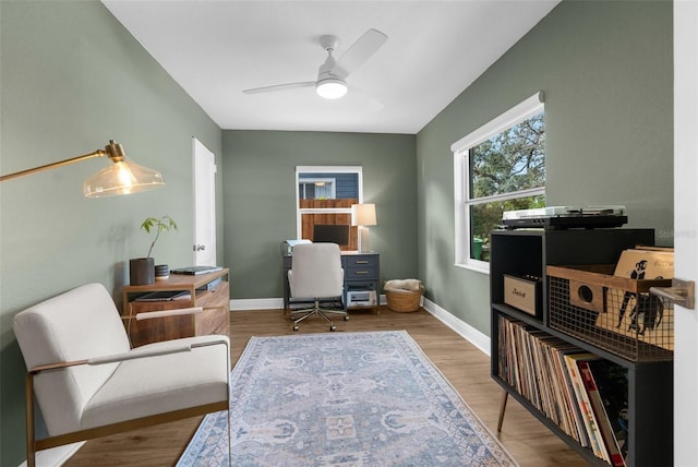 office area with a ceiling fan, light wood-type flooring, and baseboards