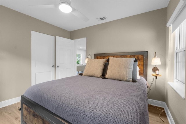 bedroom featuring a ceiling fan, visible vents, light wood-style flooring, and baseboards