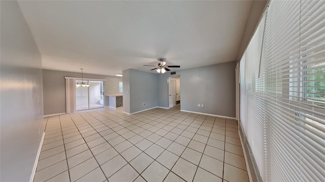 unfurnished living room with ceiling fan with notable chandelier, plenty of natural light, and light tile patterned floors