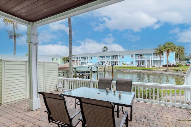 view of patio featuring outdoor dining area, a water view, boat lift, and a residential view