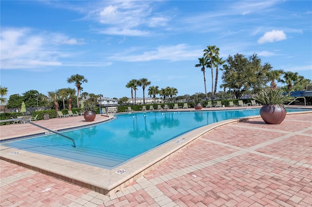 community pool with a patio area and fence