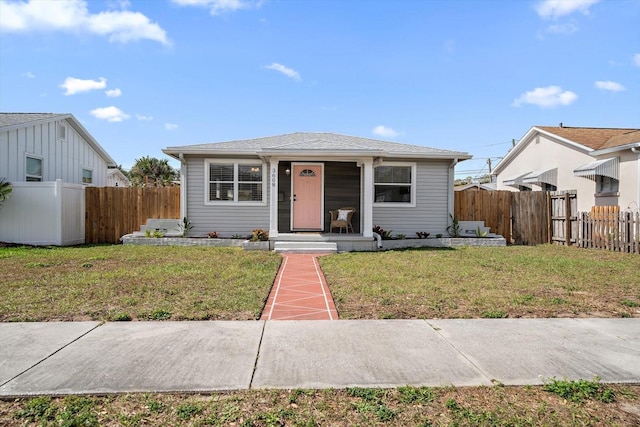 bungalow-style house featuring fence and a front lawn