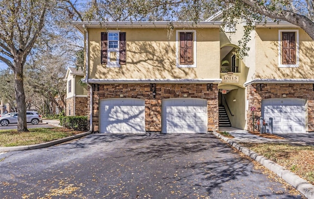 view of front of house with aphalt driveway, stone siding, a garage, and stucco siding