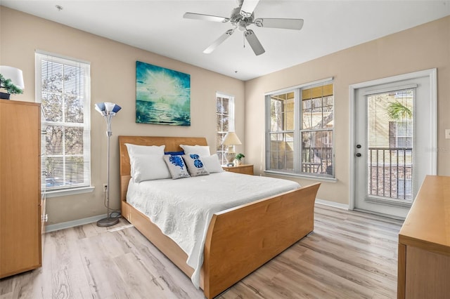 bedroom with baseboards, multiple windows, light wood-style flooring, and access to exterior