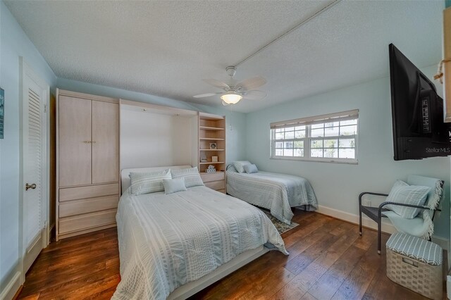 131 Bluff View Dr Unit 208, Belleair Bluffs, FL 33770 - bedroom featuring a textured ceiling, dark wood-style flooring, and a ceiling fan