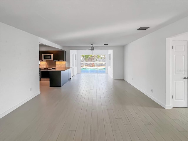 unfurnished living room with light wood-type flooring, baseboards, and visible vents