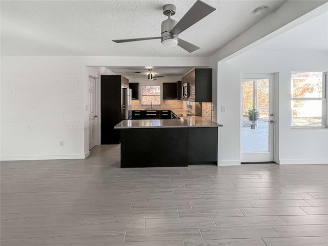 kitchen with open floor plan, a healthy amount of sunlight, a peninsula, and decorative backsplash