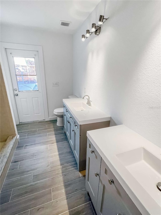 bathroom featuring wood tiled floor, visible vents, vanity, and toilet