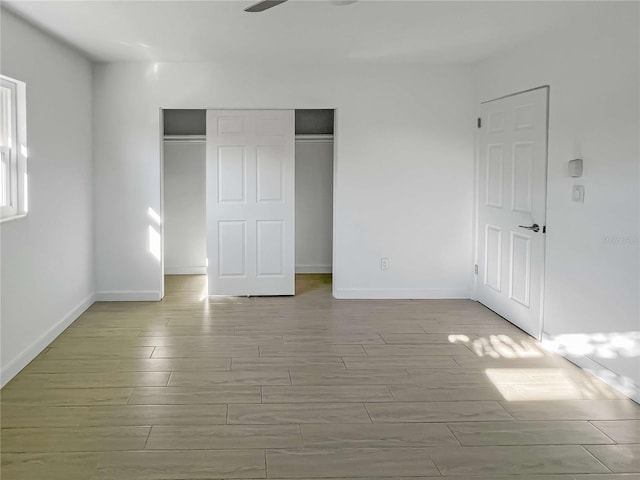 unfurnished bedroom featuring wood tiled floor, a closet, and baseboards