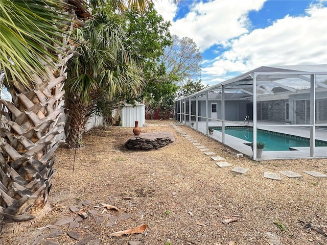 view of yard featuring a lanai, a storage shed, an outdoor pool, and an outbuilding