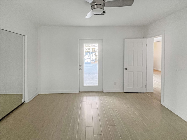 empty room with visible vents, ceiling fan, light wood-style flooring, and baseboards