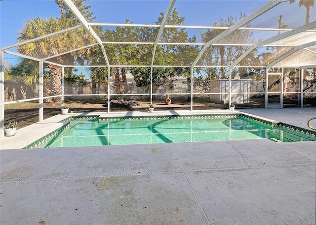 view of pool featuring glass enclosure, a storage unit, a fenced backyard, and a fenced in pool