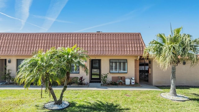 view of front facade featuring a tile roof, a front lawn, and stucco siding