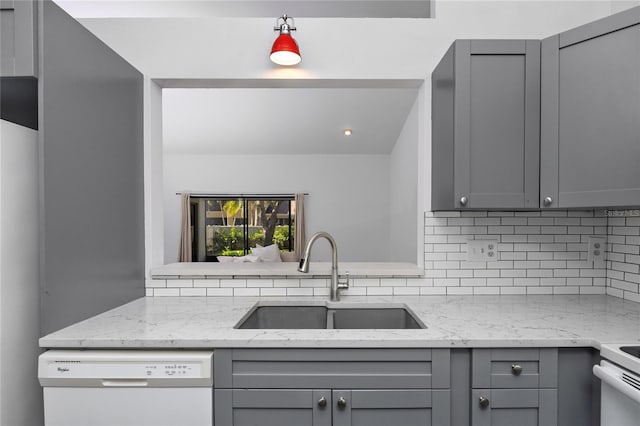 kitchen featuring light stone counters, white appliances, a sink, and gray cabinetry