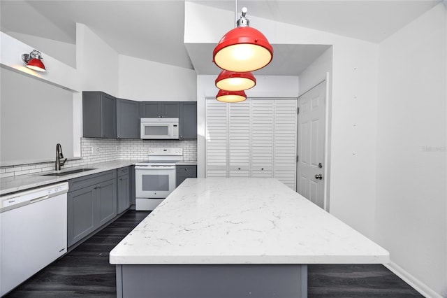 kitchen featuring white appliances, decorative backsplash, a kitchen island, gray cabinets, and a sink