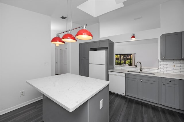 kitchen with white appliances, visible vents, a center island, gray cabinetry, and a sink