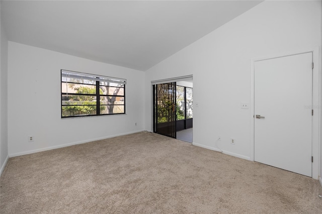 spare room featuring high vaulted ceiling, light carpet, and baseboards