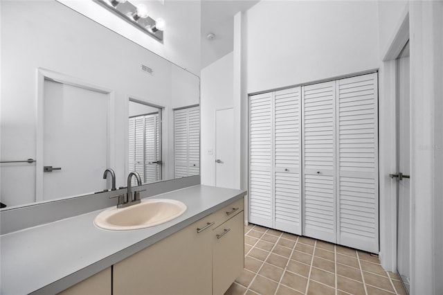 bathroom featuring visible vents, a towering ceiling, tile patterned floors, vanity, and a closet