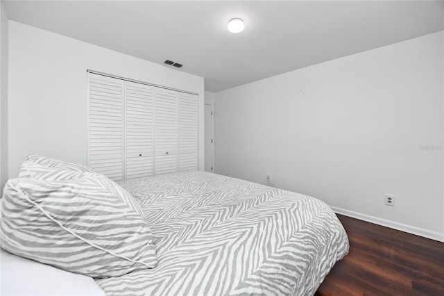 bedroom featuring dark wood-style floors, baseboards, visible vents, and a closet