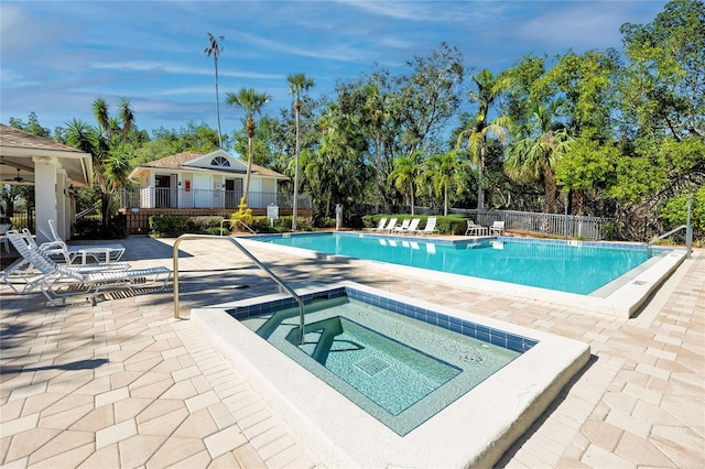 pool featuring a patio area, fence, and a hot tub