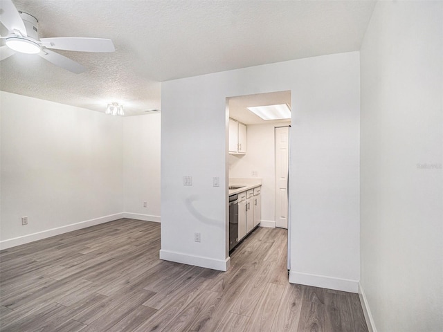 kitchen with white cabinetry, light countertops, light wood-type flooring, and stainless steel dishwasher