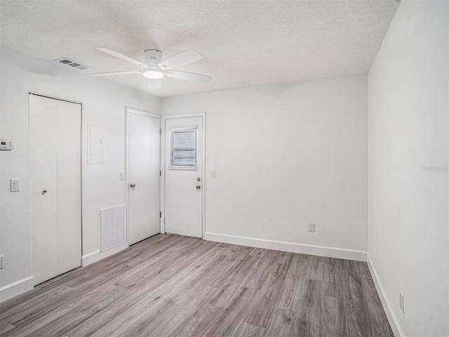 unfurnished bedroom featuring baseboards, wood finished floors, visible vents, and a textured ceiling