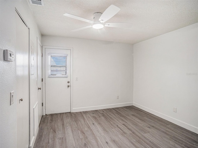 empty room featuring baseboards, a textured ceiling, ceiling fan, and wood finished floors